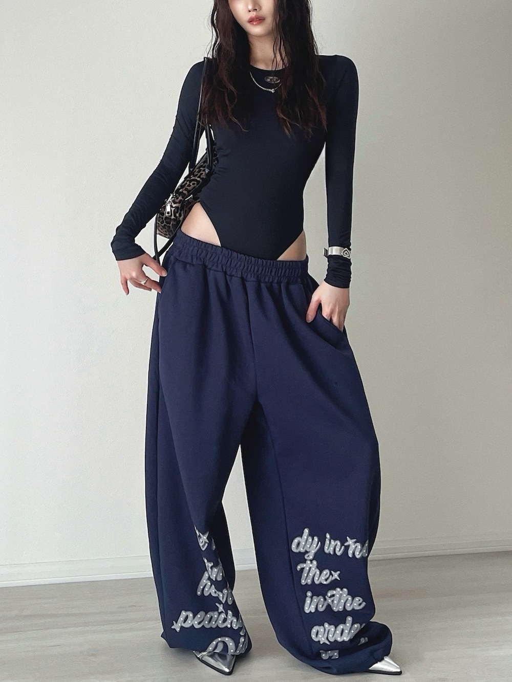 シルバー系のサンダル、ブルー系のスウェットパンツ、ブラウン系のショルダーバッグを着用したレディースの秋コーディネートの5枚目の写真