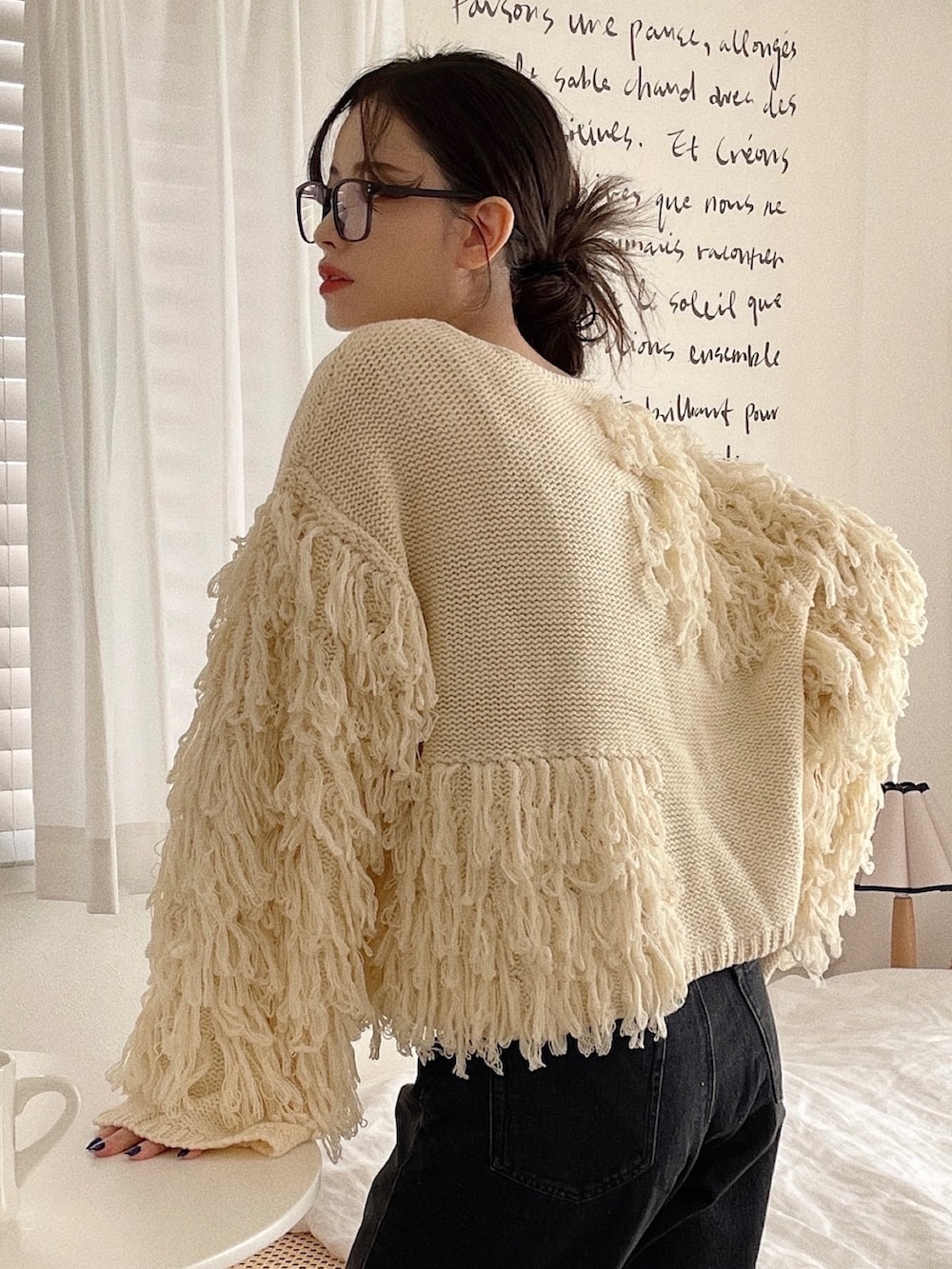 ホワイト系のニット/セーター、グレー系のショルダーバッグ、ブラック系のデニムパンツを着用したレディースの冬コーディネートの3枚目の写真