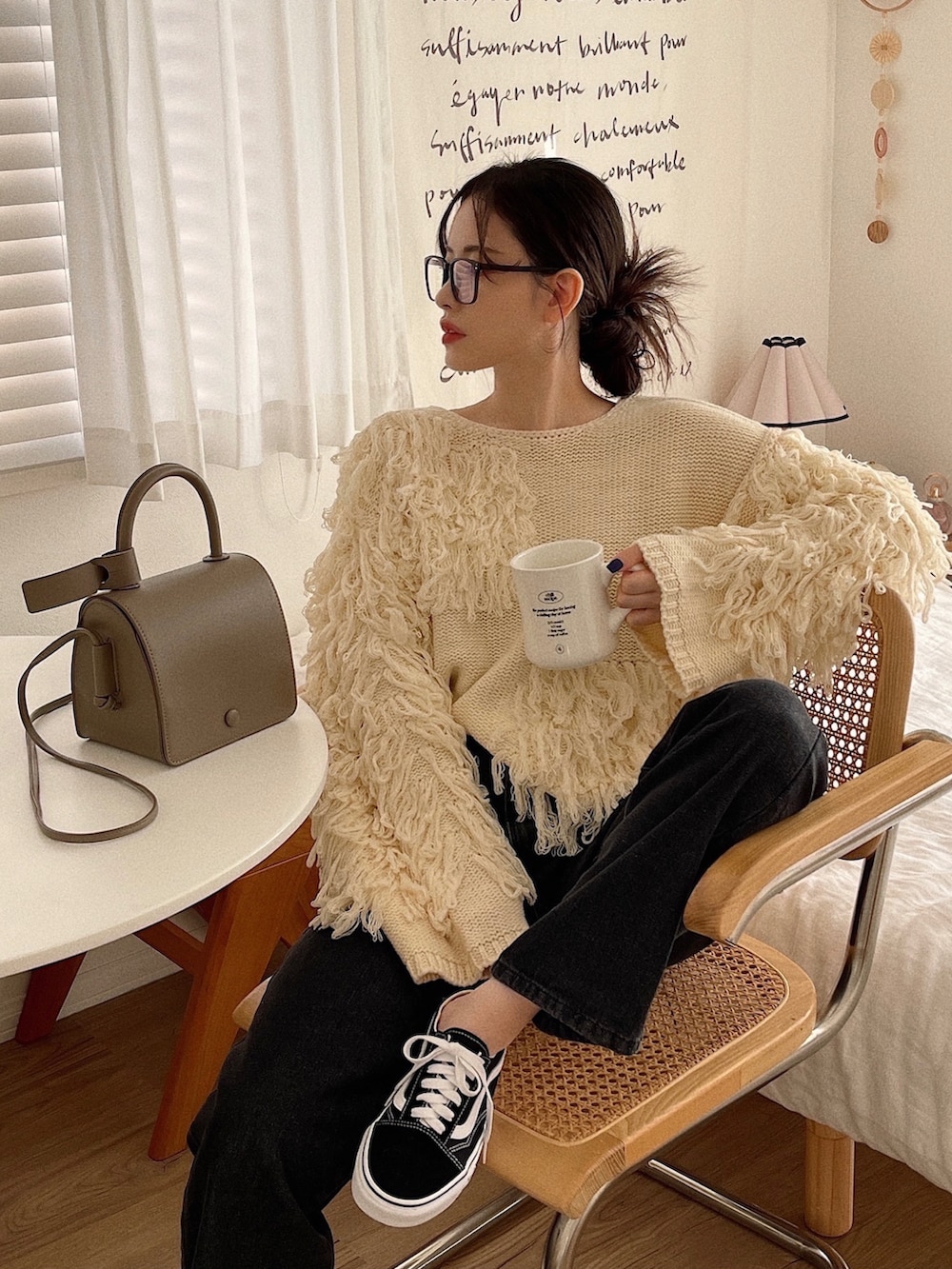 ホワイト系のニット/セーター、グレー系のショルダーバッグ、ブラック系のデニムパンツを着用したレディースの冬コーディネートの2枚目の写真