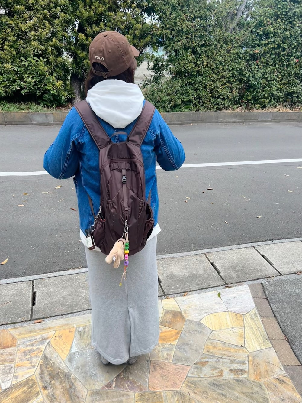 ブルー系のデニムジャケット、ホワイト系のパーカー、グレー系のスカートを着用したレディースの春コーディネートの2枚目の写真