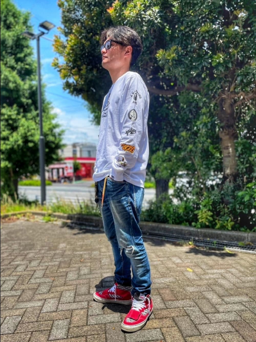 ホワイト系のTシャツ/カットソー、ブルー系のデニムパンツ、レッド系のスニーカーを着用したメンズの夏コーディネートの2枚目の写真