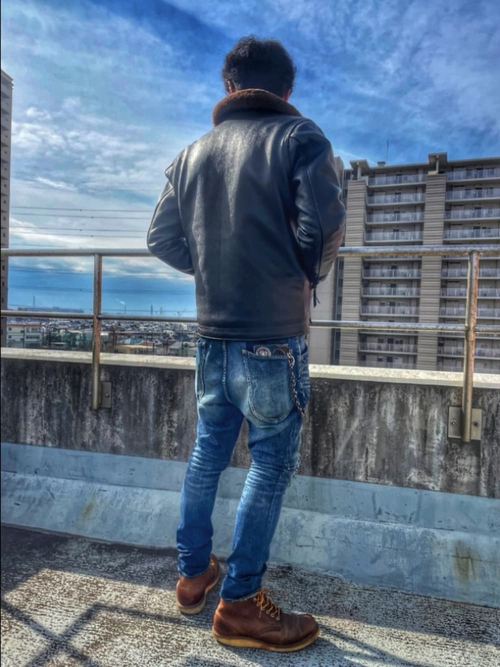 ブラック系のミリタリージャケット、オレンジ系のシャツ/ブラウス、ブルー系のデニムパンツを着用したメンズの冬コーディネートの3枚目の写真