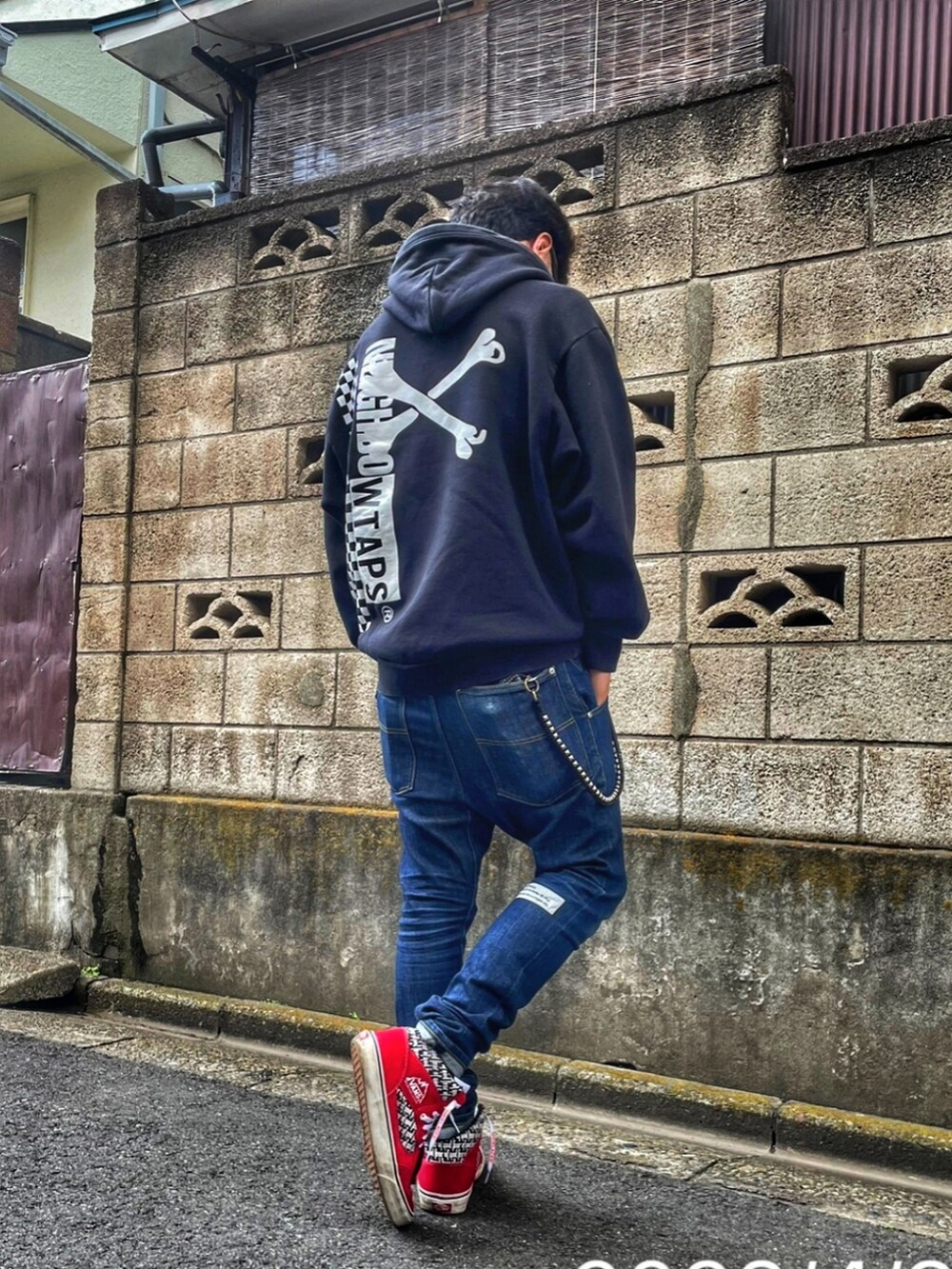 ブラック系のパーカー、ブルー系のデニムパンツ、レッド系のスニーカーを着用したメンズの春コーディネートの2枚目の写真