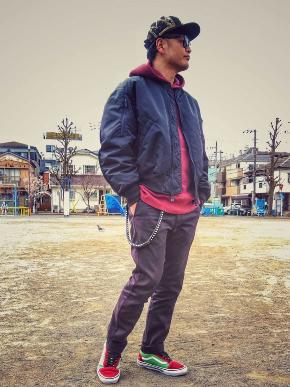 ブラック系のミリタリージャケット、レッド系のパーカー、ブラック系のチノパンツを着用したメンズの春コーディネートの3枚目の写真