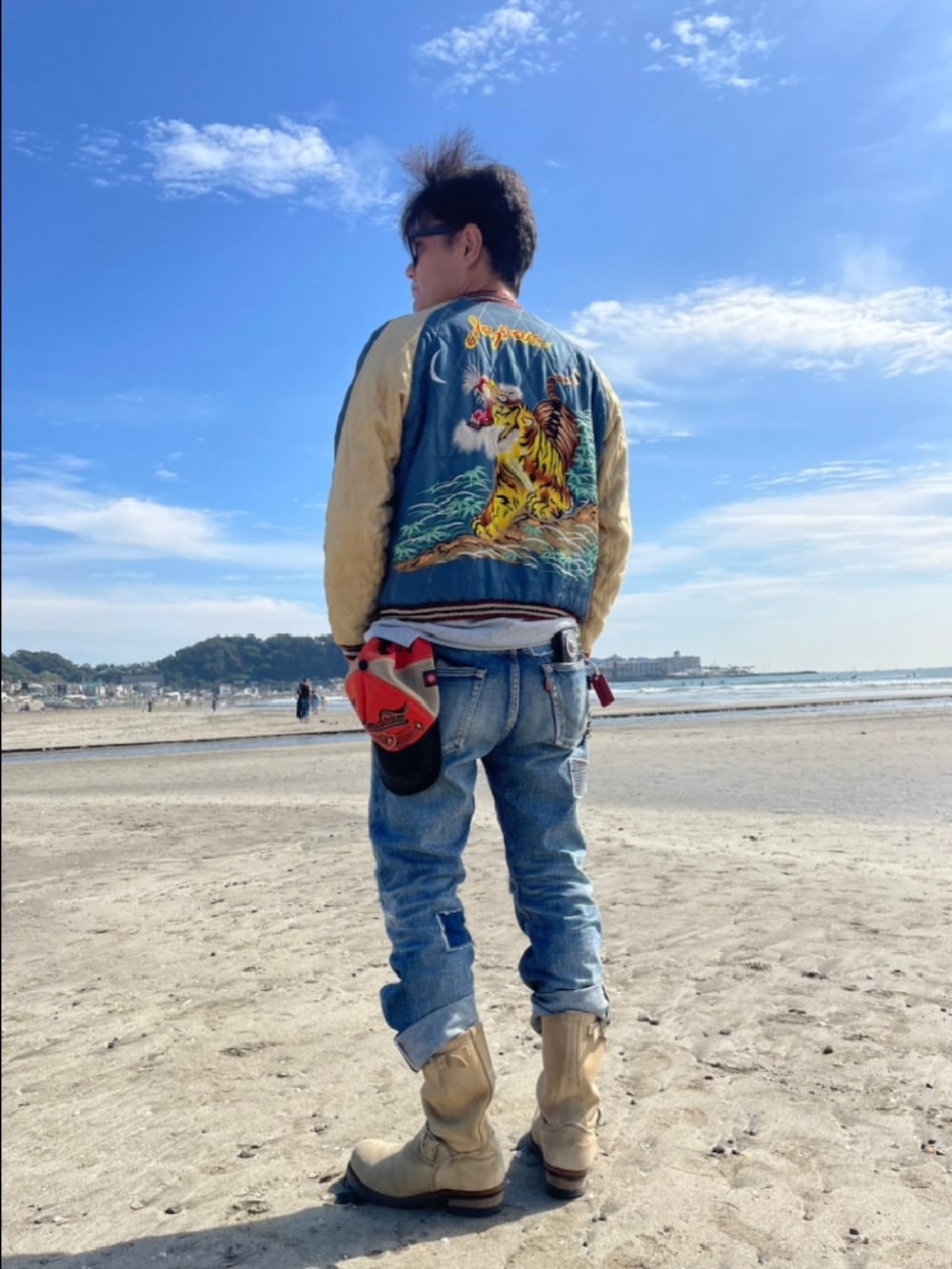 ブルー系のデニムパンツ、ベージュ系のブーツ、ブルー系のスカジャンを着用したメンズの秋コーディネートの2枚目の写真