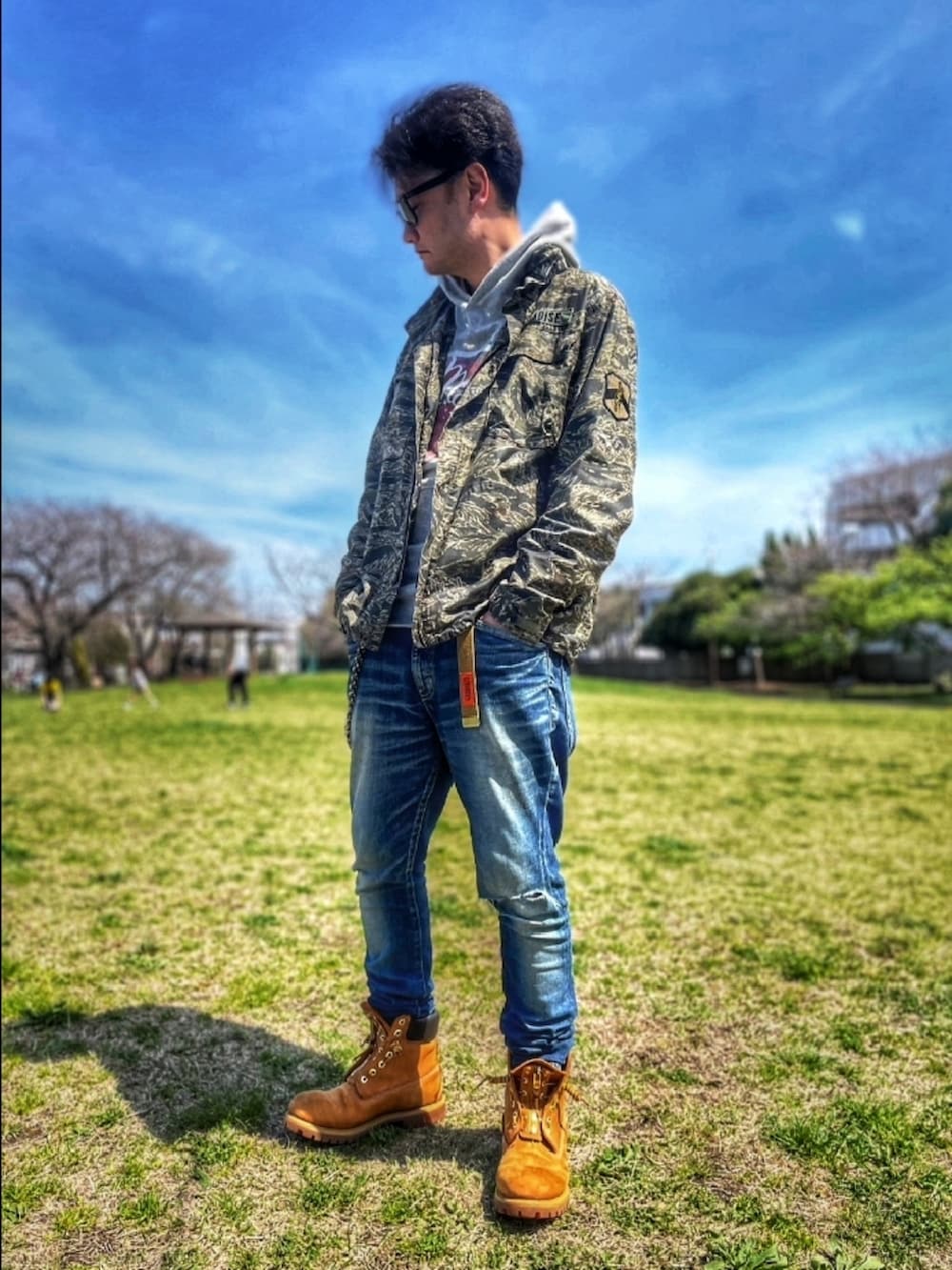 その他のミリタリージャケット、グレー系のパーカー、ブルー系のデニムパンツを着用したメンズの春コーディネートの2枚目の写真