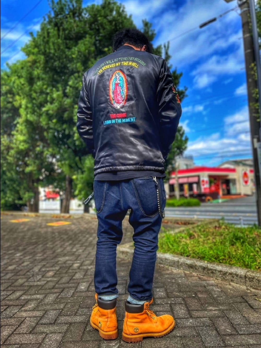 ブラック系のナイロンジャケット、イエロー系のブーツ、ブルー系のデニムパンツを着用したメンズの春コーディネートの2枚目の写真