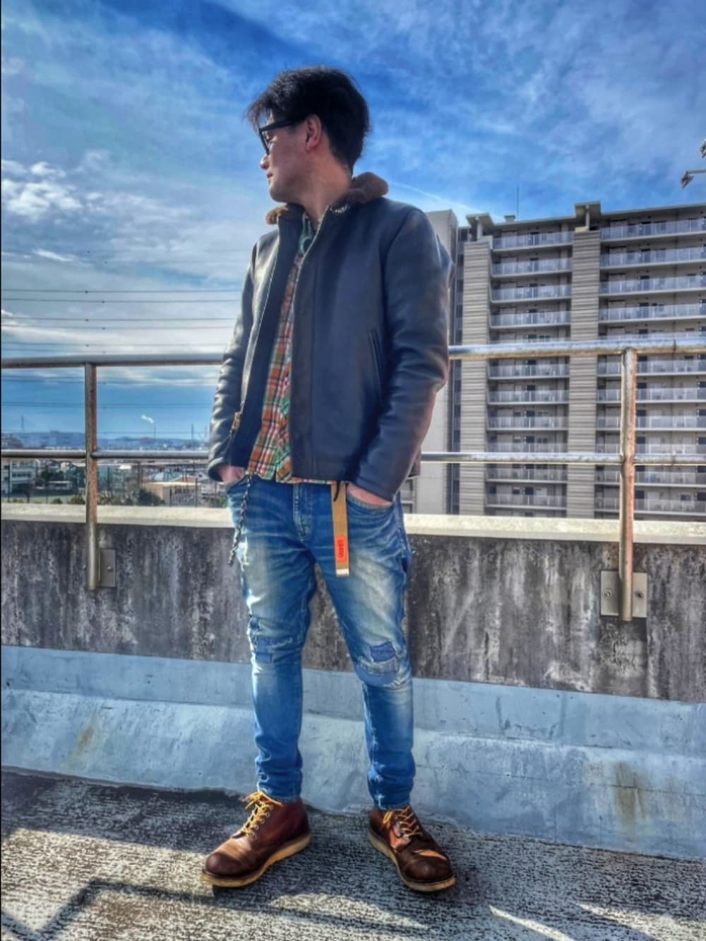 ブラック系のミリタリージャケット、オレンジ系のシャツ/ブラウス、ブルー系のデニムパンツを着用したメンズの冬コーディネートの2枚目の写真