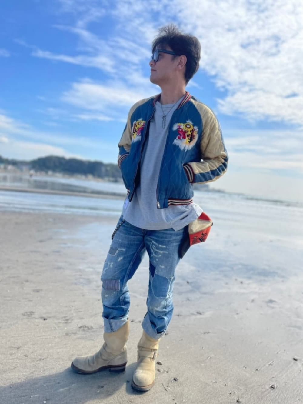 ブルー系のスカジャン、ベージュ系のブーツ、ブルー系のデニムパンツを着用したメンズの春コーディネートの2枚目の写真