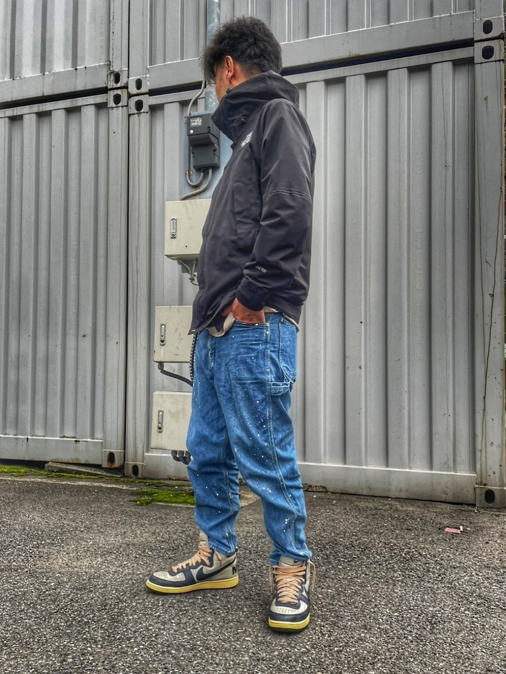 ブラック系のナイロンジャケット、ブルー系のデニムパンツ、グレー系のスニーカーを着用したメンズの春コーディネートの2枚目の写真