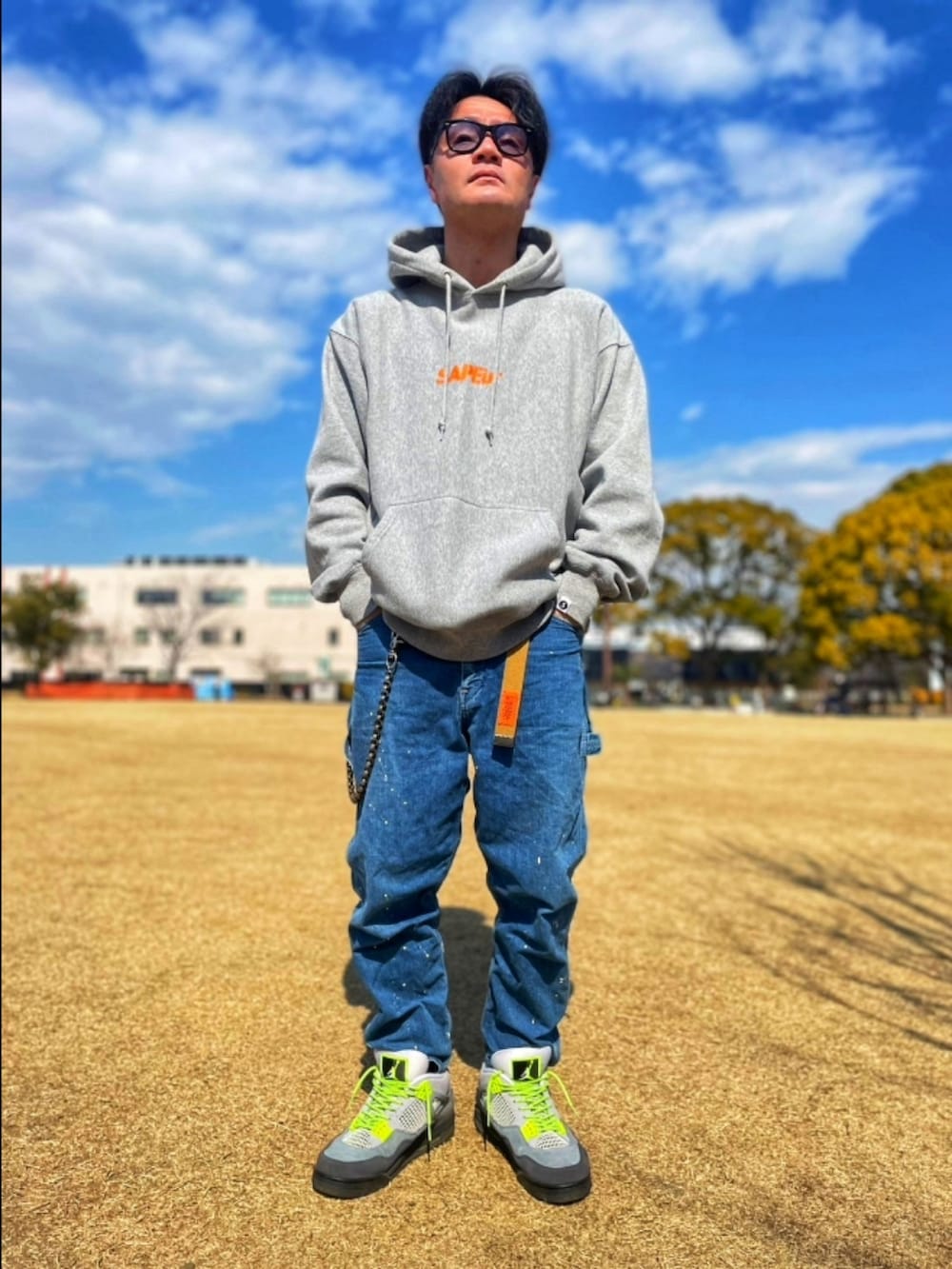 グレー系のパーカー、ブルー系のデニムパンツ、グレー系のスニーカーを着用したメンズの春コーディネートの2枚目の写真