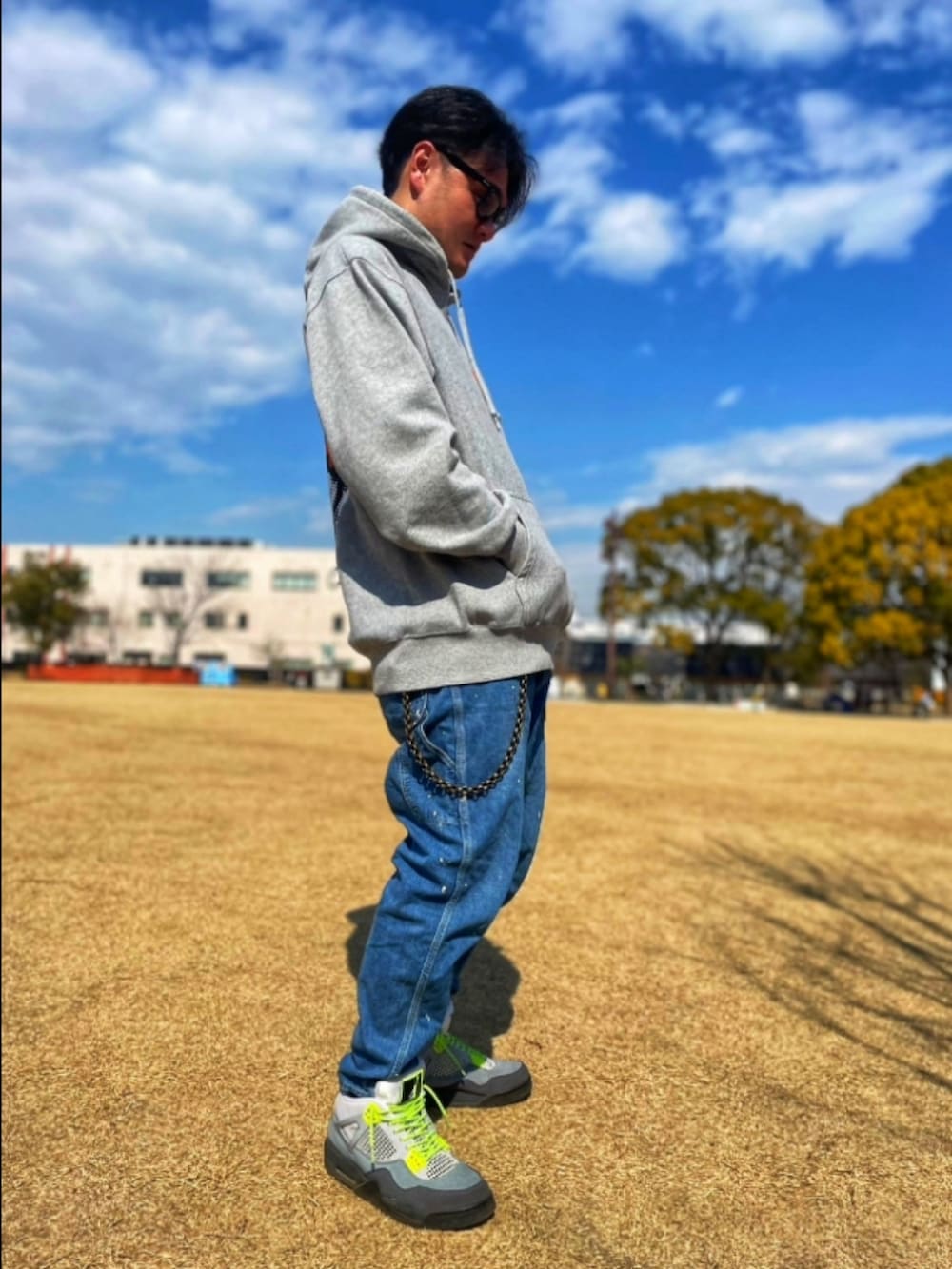 グレー系のパーカー、ブルー系のデニムパンツ、グレー系のスニーカーを着用したメンズの春コーディネートの3枚目の写真