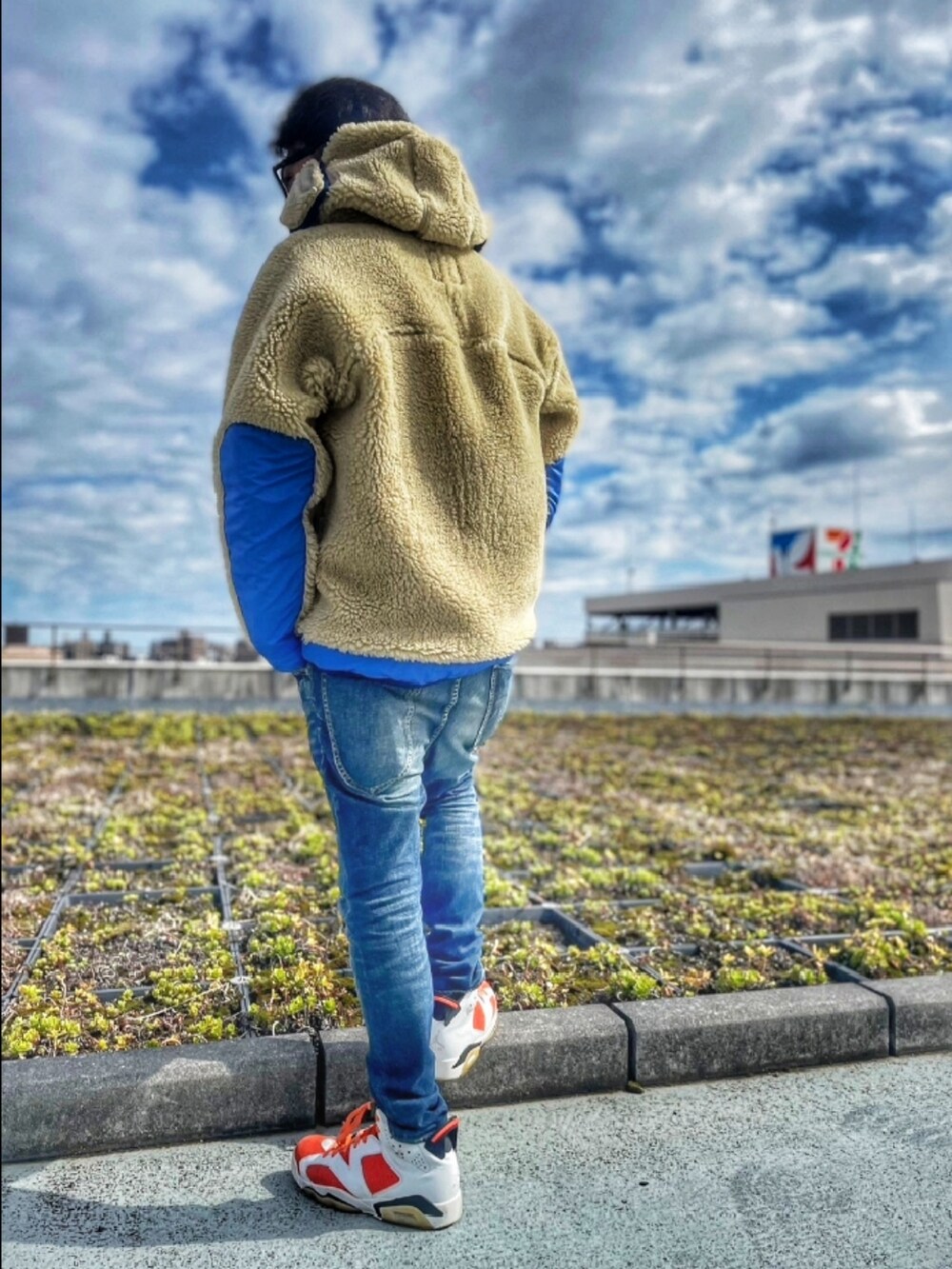 ベージュ系のブルゾン、ブルー系のデニムパンツ、オレンジ系のパーカーを着用したメンズの春コーディネートの3枚目の写真