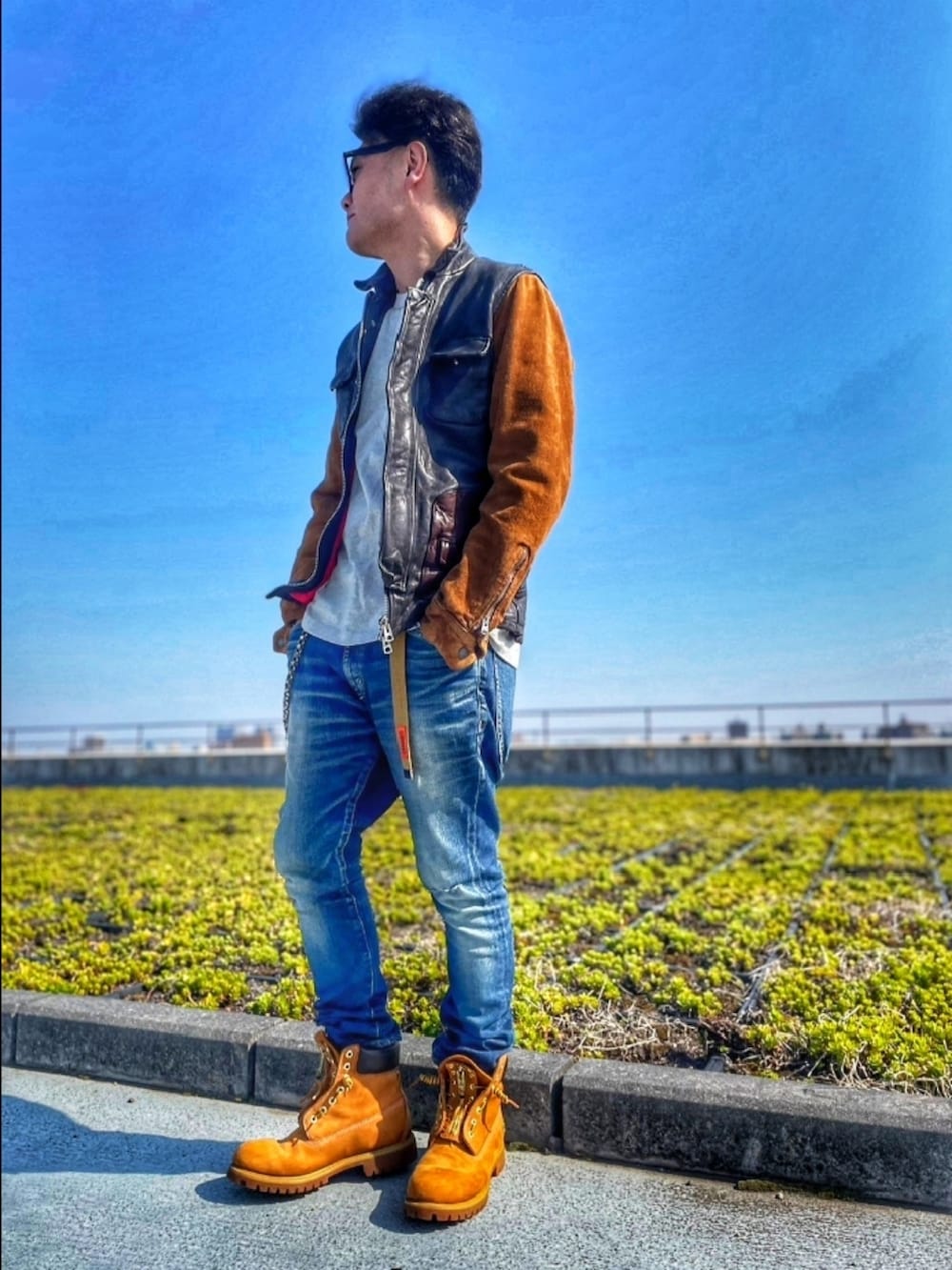 ブルー系のライダースジャケット、ブルー系のデニムパンツ、イエロー系のブーツを着用したメンズの春コーディネートの2枚目の写真