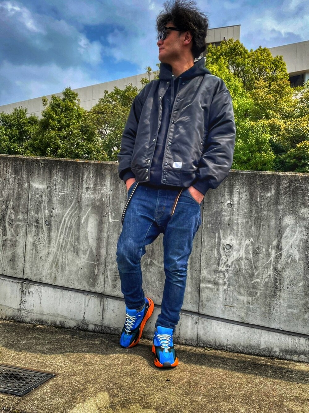 ブラック系のナイロンジャケット、ブルー系のデニムパンツ、ブルー系のスニーカーを着用したメンズの春コーディネートの3枚目の写真