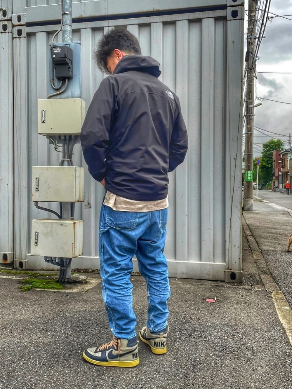 ブラック系のナイロンジャケット、ブルー系のデニムパンツ、グレー系のスニーカーを着用したメンズの春コーディネートの3枚目の写真