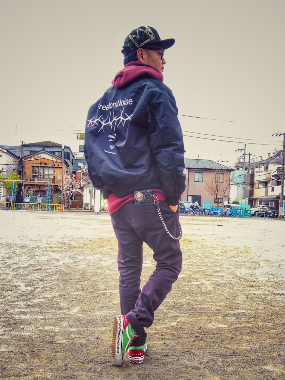 ブラック系のミリタリージャケット、レッド系のパーカー、ブラック系のチノパンツを着用したメンズの春コーディネートの2枚目の写真