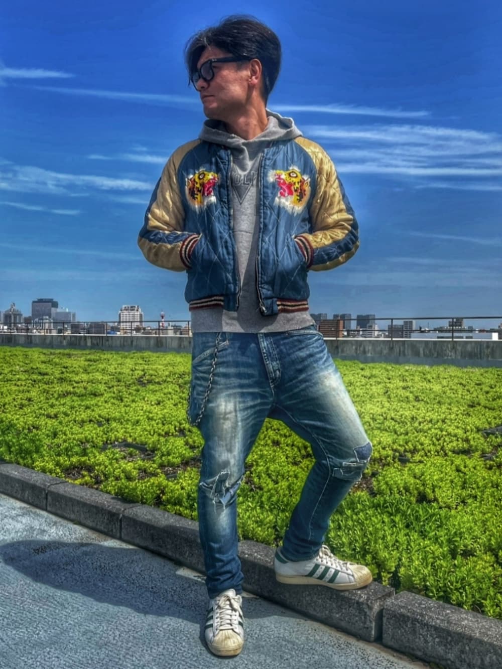 ブルー系のスカジャン、ブルー系のデニムパンツ、ホワイト系のスニーカーを着用したメンズの春コーディネートの3枚目の写真