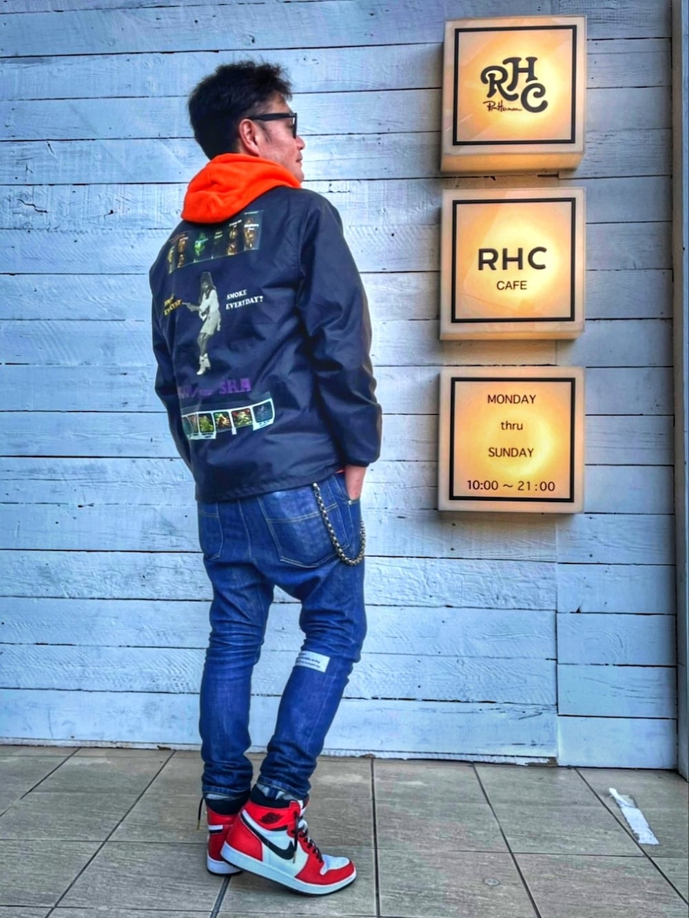 ブラック系のナイロンジャケット、ブルー系のデニムパンツ、ホワイト系のスニーカーを着用したメンズの秋コーディネートの2枚目の写真