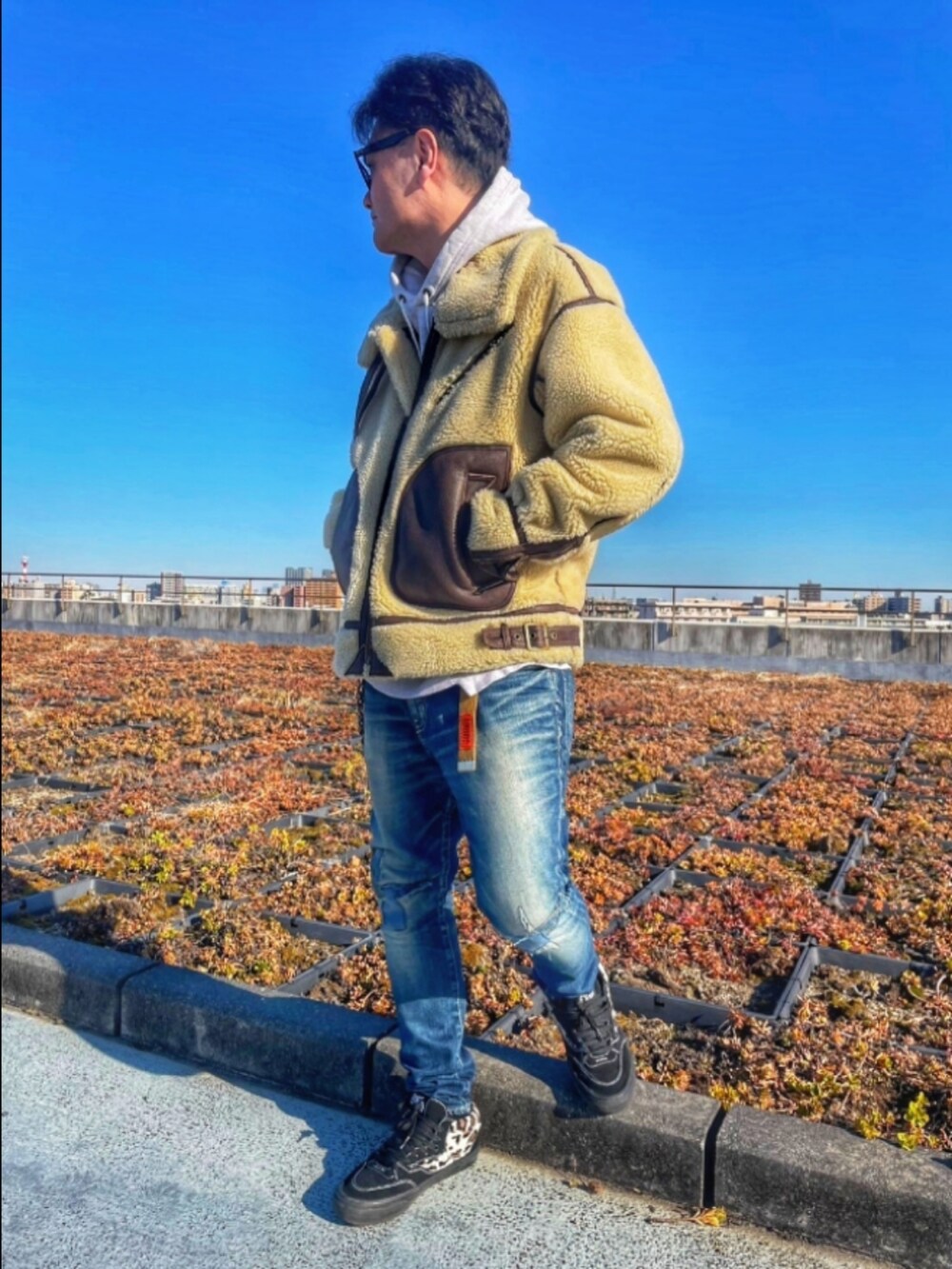 ブルー系のデニムパンツ、ブラック系のスニーカー、グレー系のパーカーを着用したメンズの冬コーディネートの2枚目の写真