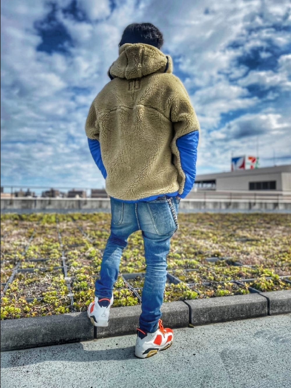 ベージュ系のブルゾン、ブルー系のデニムパンツ、オレンジ系のパーカーを着用したメンズの春コーディネートの4枚目の写真