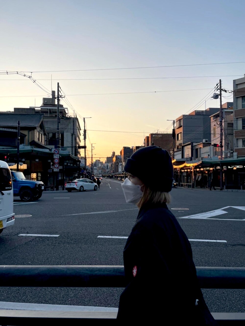 ブラック系のステンカラーコート、ブラック系のサンダル、ブルー系のスウェットパンツを着用したレディースの春コーディネートの2枚目の写真