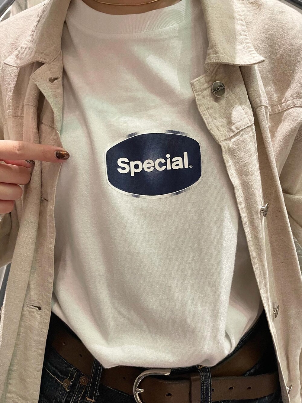 ブラック系のデニムパンツ、ホワイト系のTシャツ/カットソー、ベージュ系のジャケット/アウターを着用したレディースの夏コーディネートの2枚目の写真