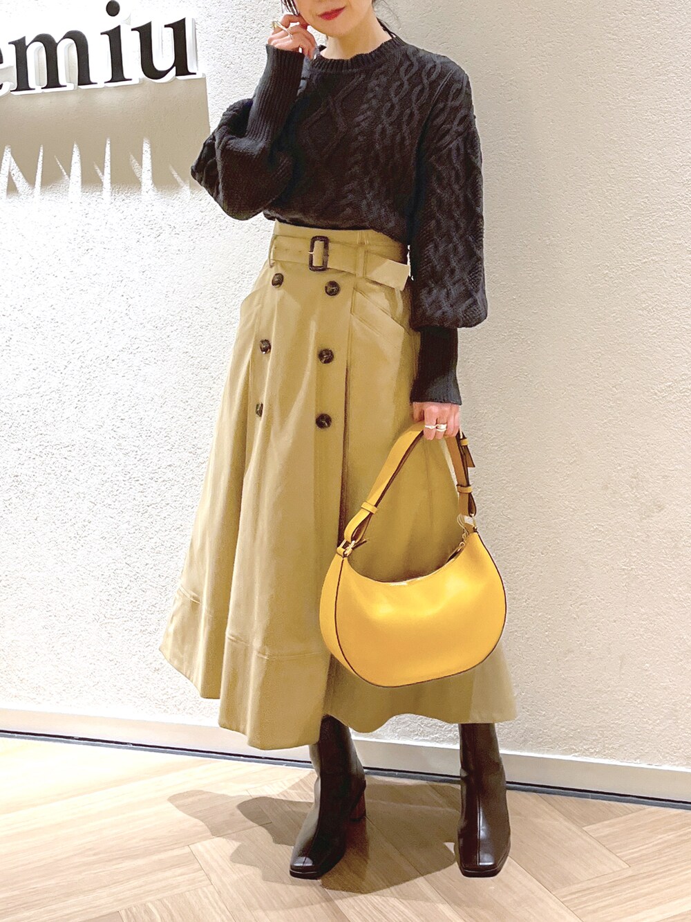 グレー系のニット/セーター、ベージュ系のスカート、イエロー系のショルダーバッグを着用したレディースの冬コーディネートの2枚目の写真