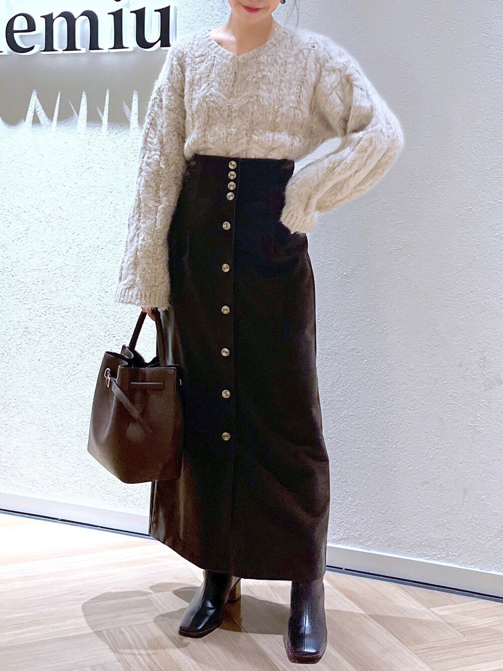 ブラウン系のチェスターコート、ホワイト系のニット/セーター、ブラウン系のショルダーバッグを着用したレディースの冬コーディネートの2枚目の写真