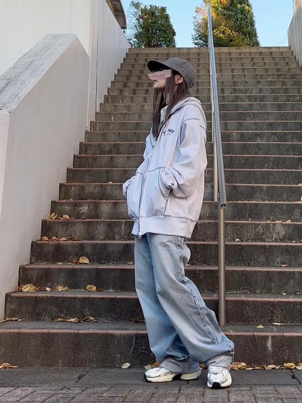 ブルー系のデニムパンツ、ホワイト系のスニーカー、グレー系のパーカーを着用したレディースの秋コーディネートの2枚目の写真