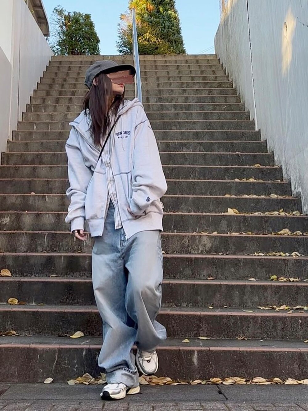 ブルー系のデニムパンツ、ホワイト系のスニーカー、グレー系のパーカーを着用したレディースの秋コーディネートの4枚目の写真