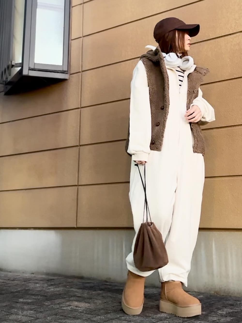 ブラウン系のブーツ、ブラウン系のショルダーバッグ、ホワイト系のつなぎ/オールインワンを着用したレディースの冬コーディネートの2枚目の写真