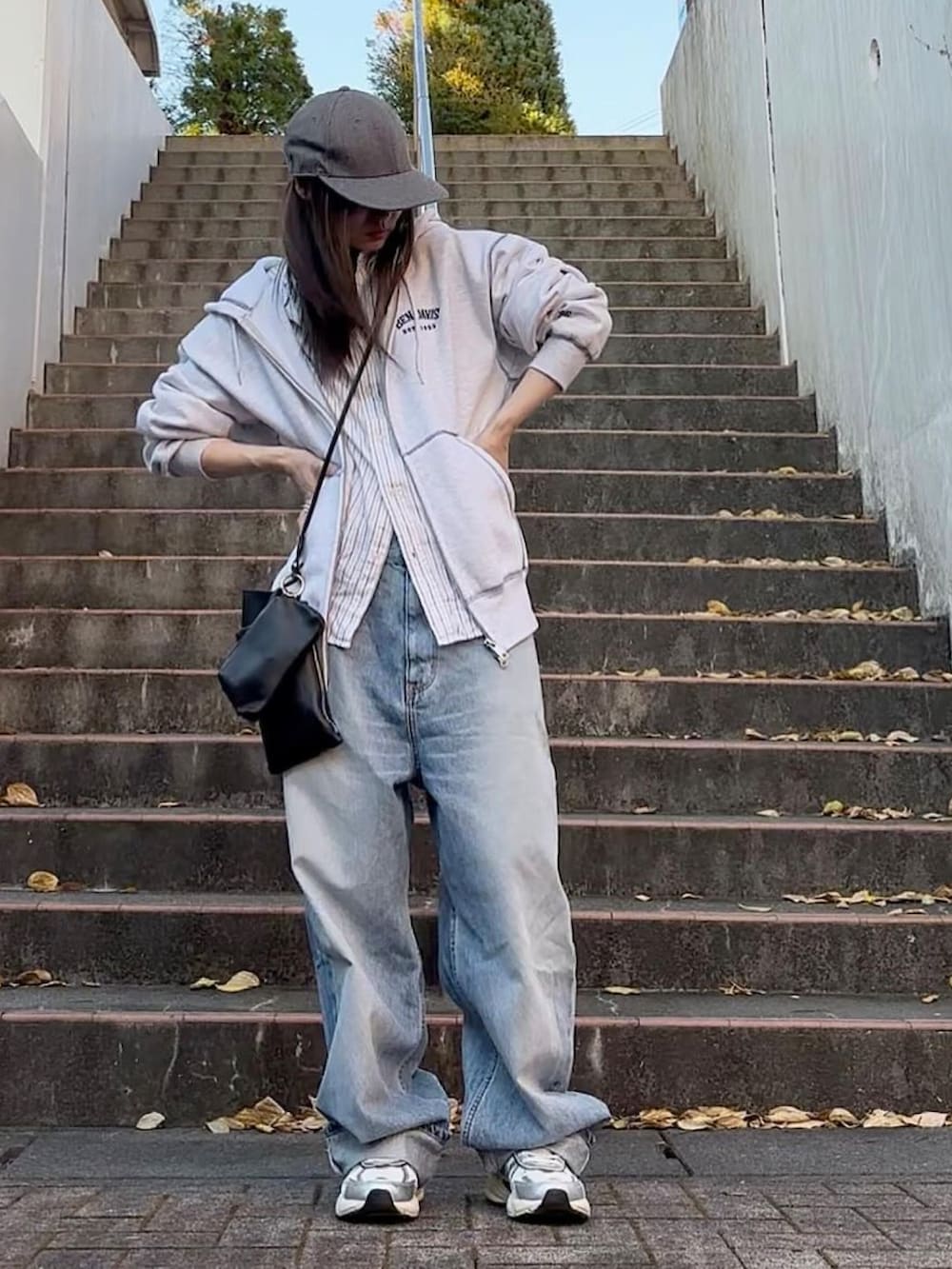 ブルー系のデニムパンツ、ホワイト系のスニーカー、グレー系のパーカーを着用したレディースの秋コーディネートの3枚目の写真