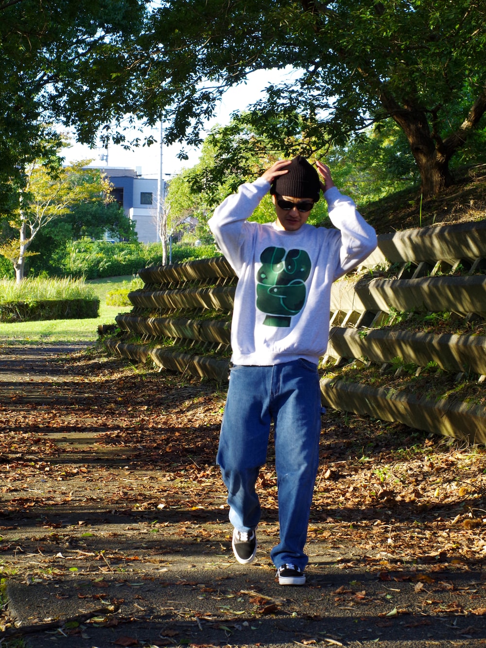 グレー系のスウェット、ブルー系のデニムパンツ、ブラック系のスニーカーを着用したメンズの秋コーディネートの2枚目の写真