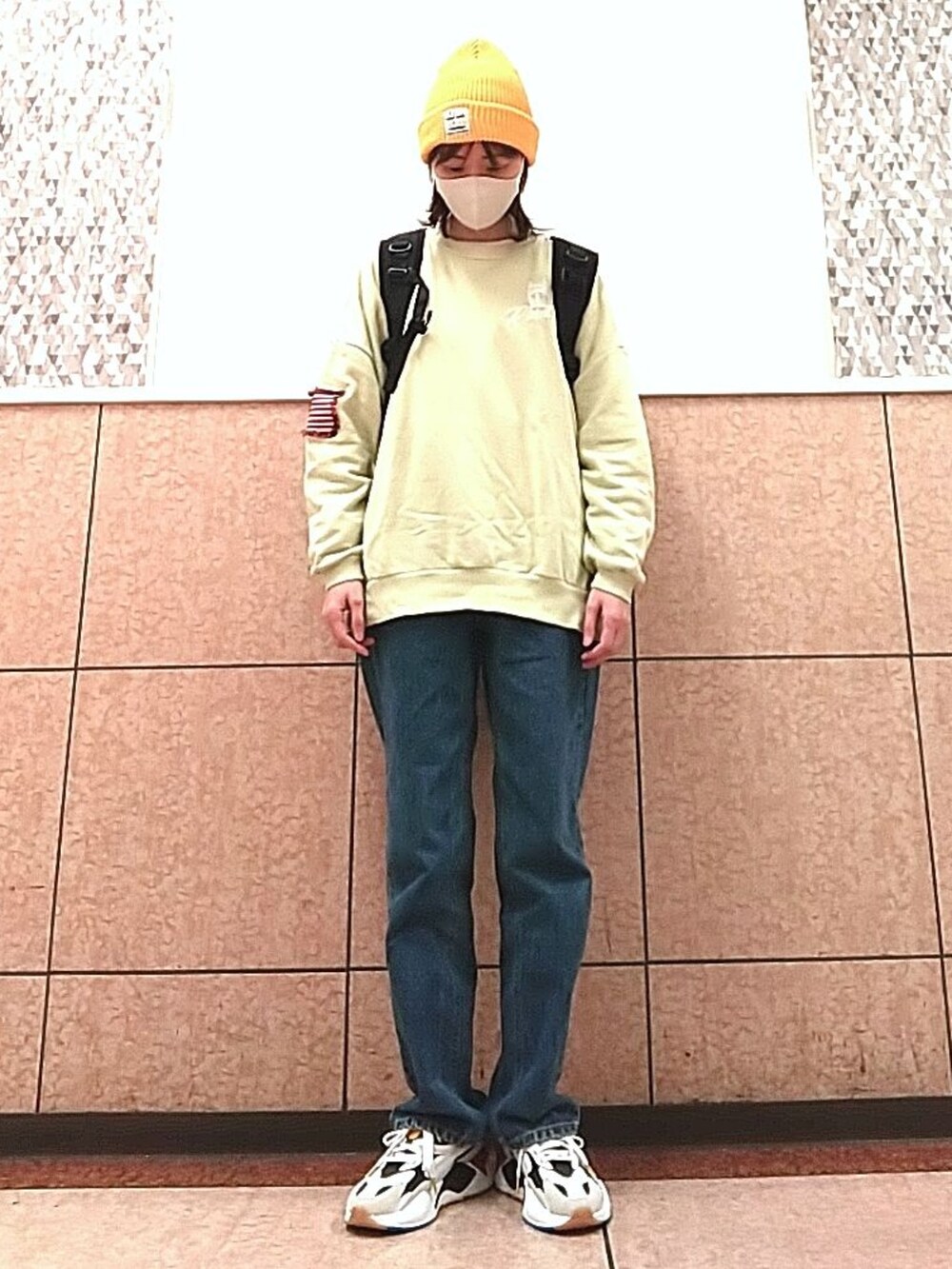 ブルー系のデニムパンツ、ブラック系のバックパック/リュック、ホワイト系のスニーカーを着用したレディースの秋コーディネートの3枚目の写真