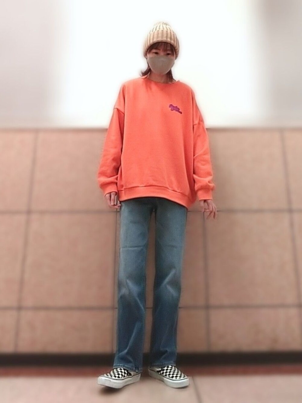 オレンジ系のTシャツ/カットソー、ブラック系のスリッポン、ブルー系のデニムパンツを着用したレディースの秋コーディネートの2枚目の写真