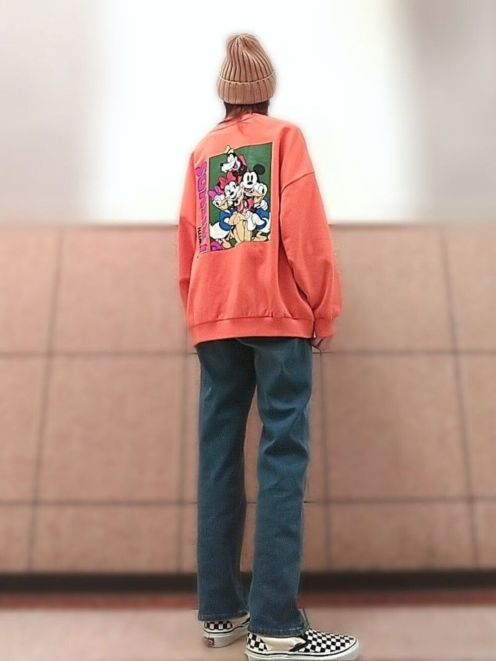 オレンジ系のTシャツ/カットソー、ブラック系のスリッポン、ブルー系のデニムパンツを着用したレディースの秋コーディネートの3枚目の写真