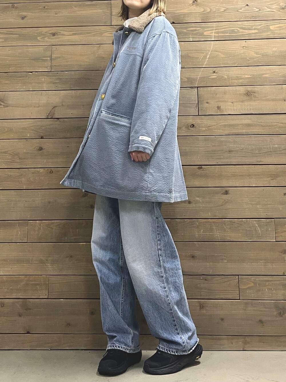 ブルー系のステンカラーコート、ブラック系のスニーカー、ホワイト系のTシャツ/カットソーを着用したレディースの冬コーディネートの2枚目の写真