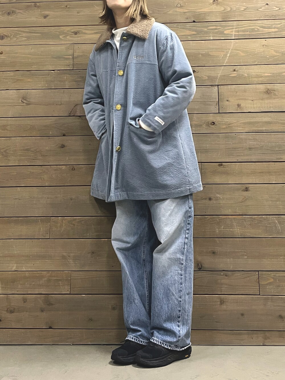 ブルー系のステンカラーコート、ブラック系のスニーカー、ホワイト系のTシャツ/カットソーを着用したレディースの冬コーディネートの3枚目の写真