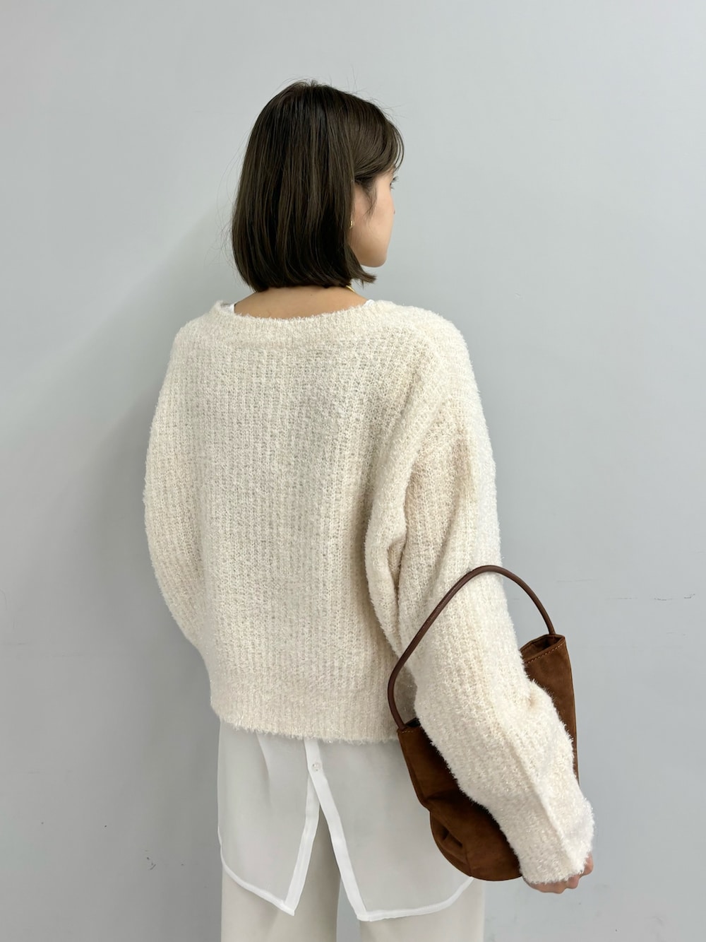 ブラウン系のトートバッグ、ホワイト系のニット/セーター、ホワイト系のシャツ/ブラウスを着用したレディースの冬コーディネートの5枚目の写真