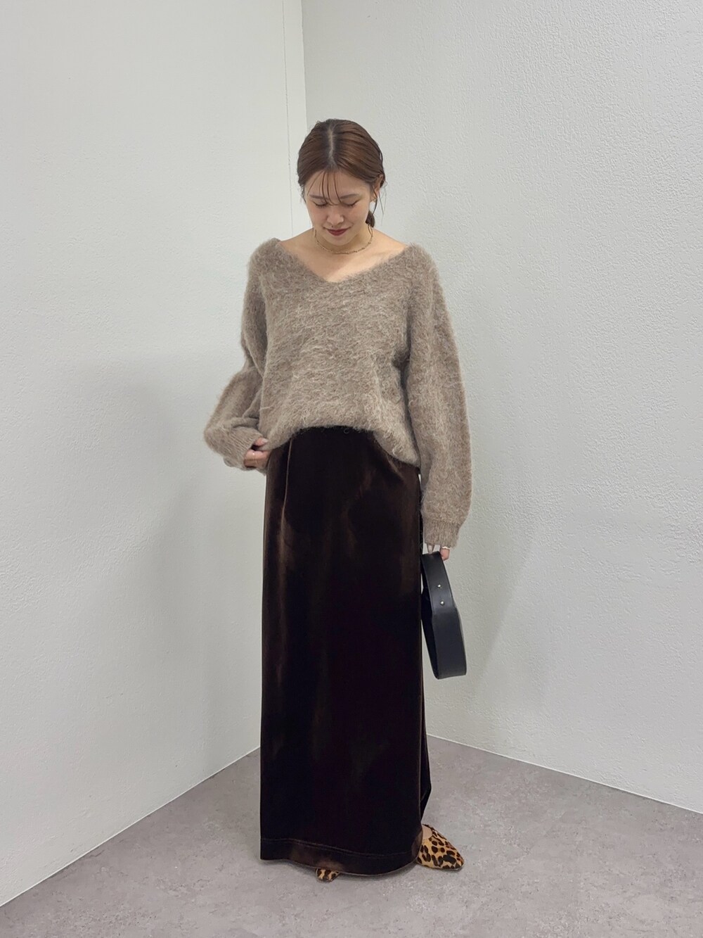ブラウン系のニット/セーター、ブラック系のトートバッグ、ブラウン系のスカートを着用したレディースの秋コーディネートの5枚目の写真