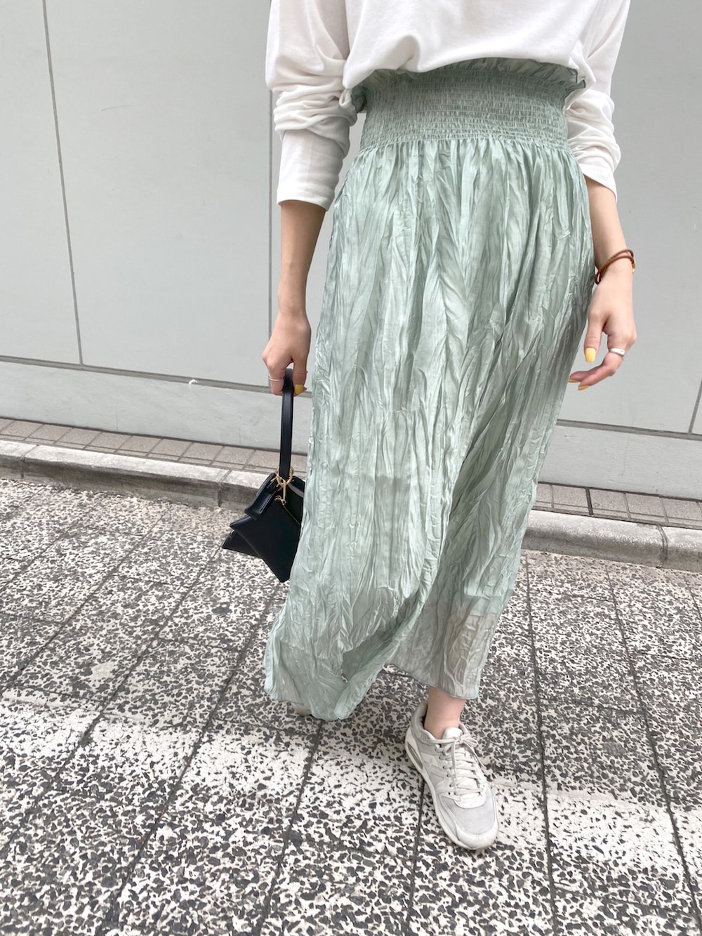 ホワイト系のTシャツ/カットソー、グリーン系のスカート、ブラック系のハンドバッグを着用したレディースの春コーディネートの5枚目の写真