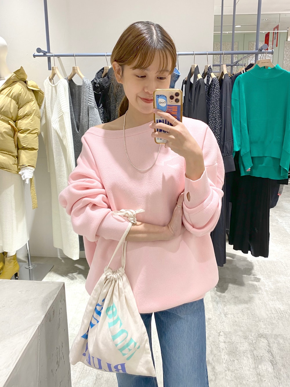 ピンク系のニット/セーター、ブルー系のデニムパンツ、ホワイト系のトートバッグを着用したレディースの冬コーディネートの2枚目の写真