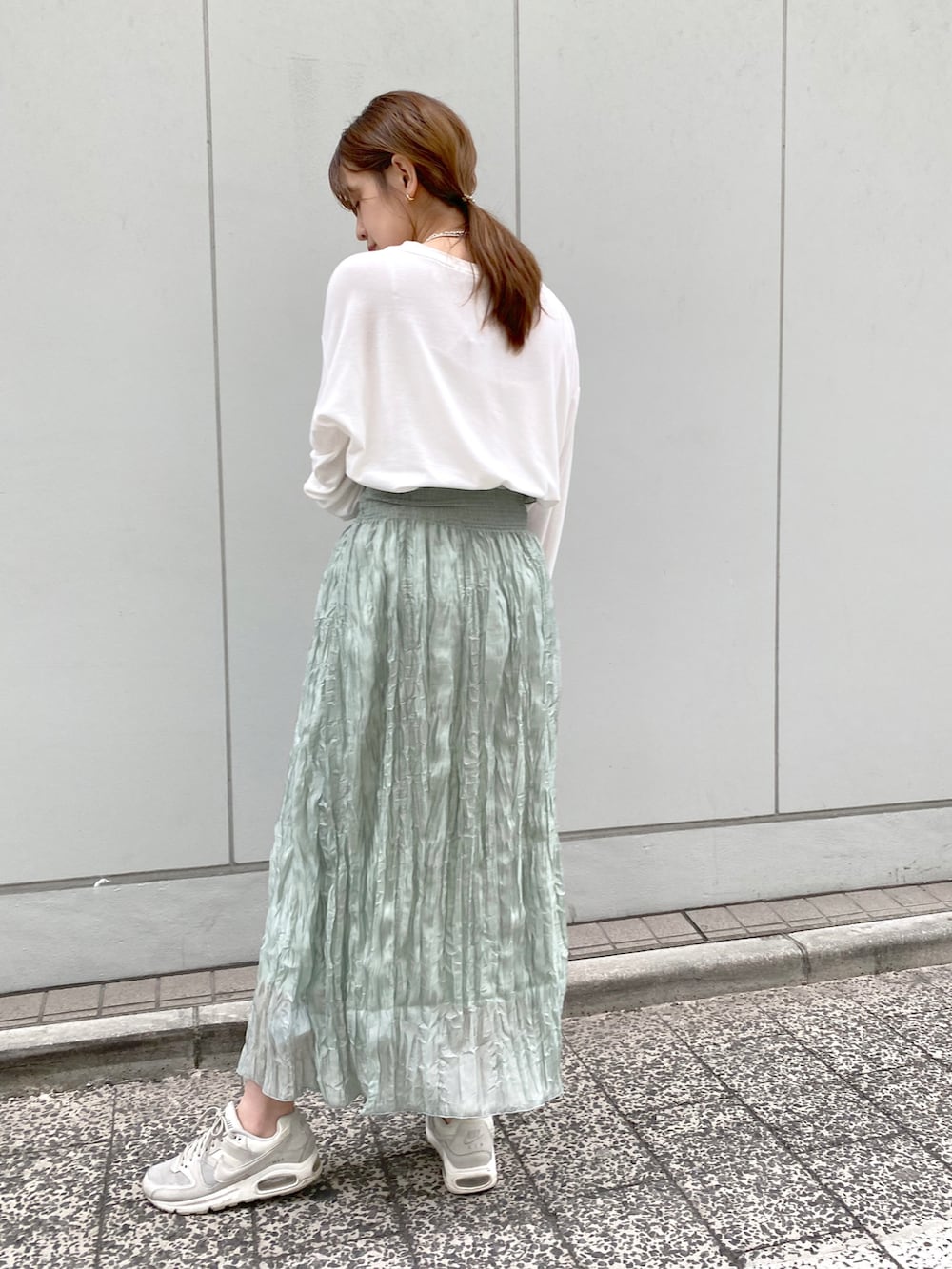 ホワイト系のTシャツ/カットソー、グリーン系のスカート、ブラック系のハンドバッグを着用したレディースの春コーディネートの2枚目の写真