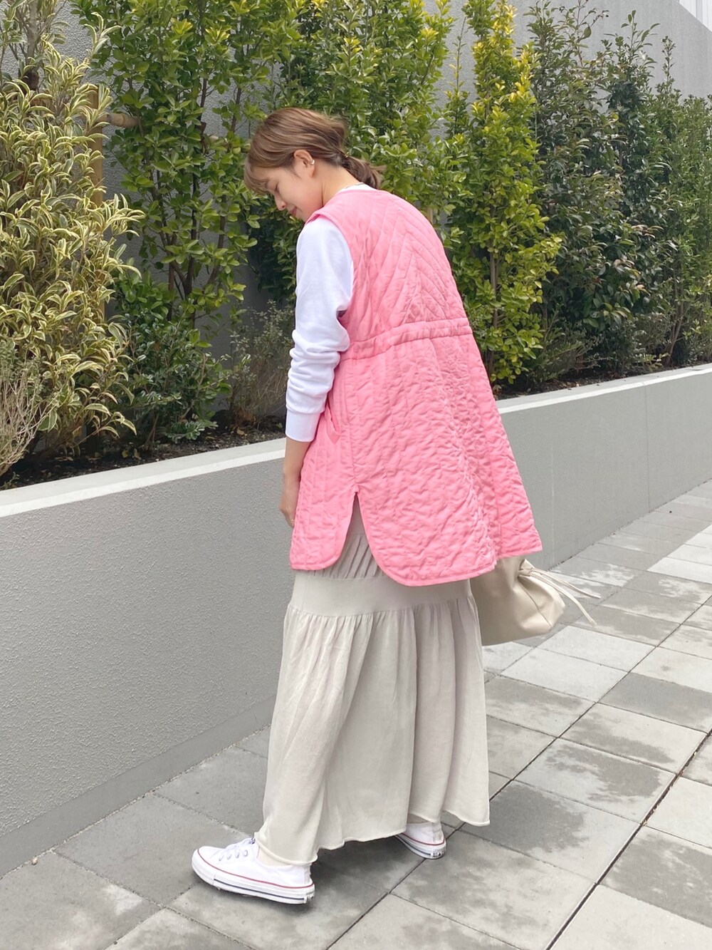 ホワイト系のスウェット、ピンク系のベスト、グレー系のスカートを着用したレディースの春コーディネートの2枚目の写真