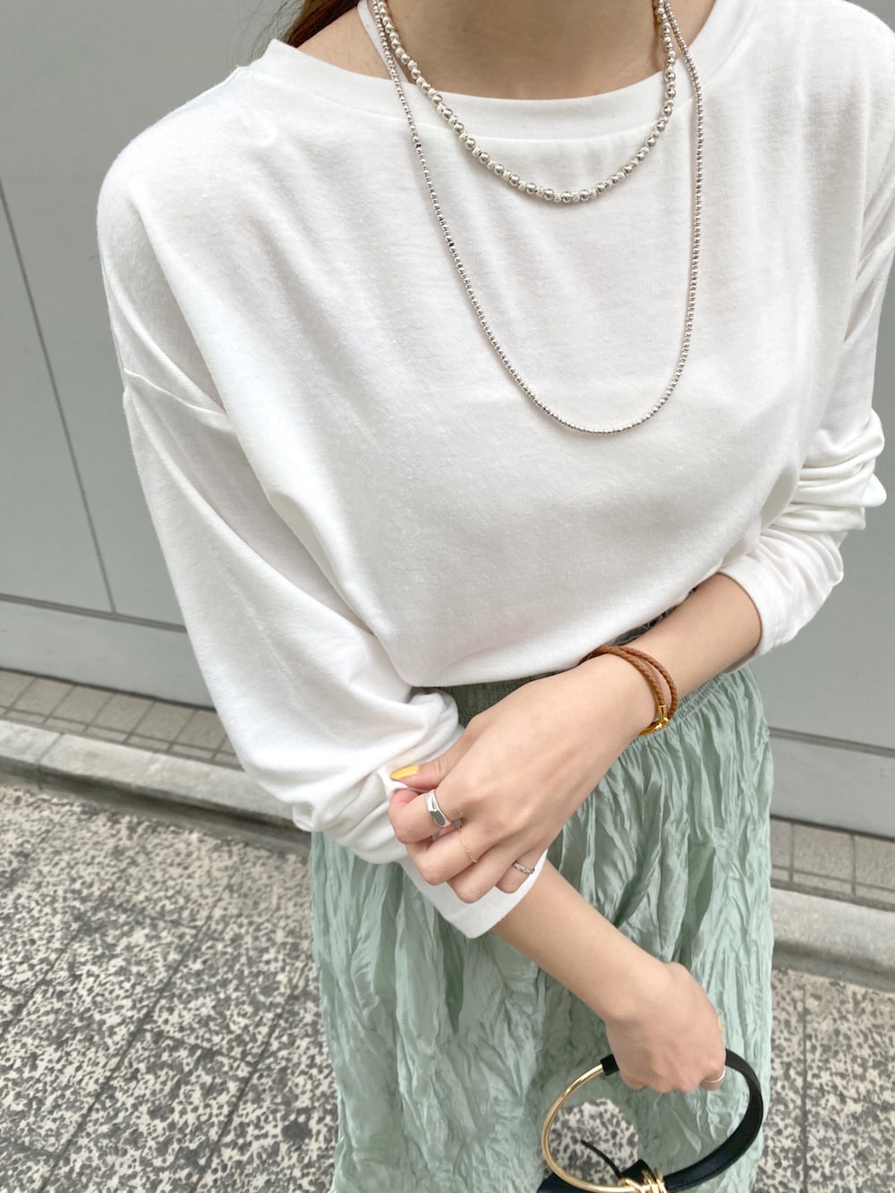ホワイト系のTシャツ/カットソー、グリーン系のスカート、ブラック系のハンドバッグを着用したレディースの春コーディネートの3枚目の写真