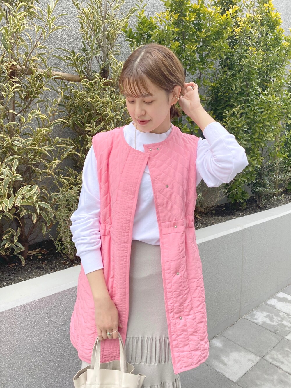 ホワイト系のスウェット、ピンク系のベスト、グレー系のスカートを着用したレディースの春コーディネートの3枚目の写真