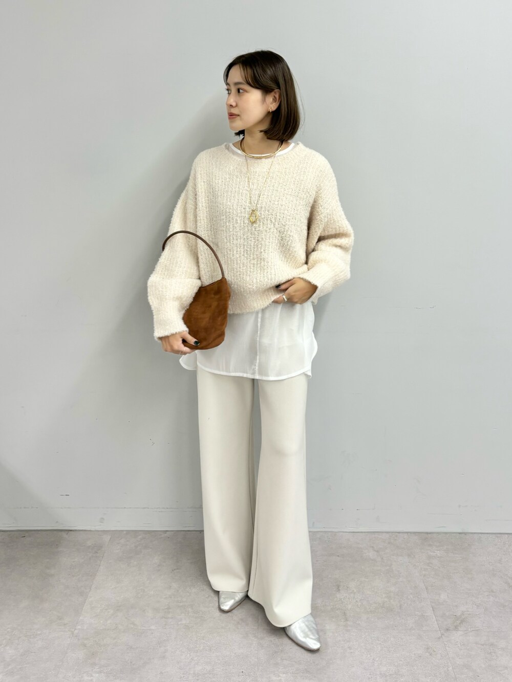 ブラウン系のトートバッグ、ホワイト系のニット/セーター、ホワイト系のシャツ/ブラウスを着用したレディースの冬コーディネートの4枚目の写真