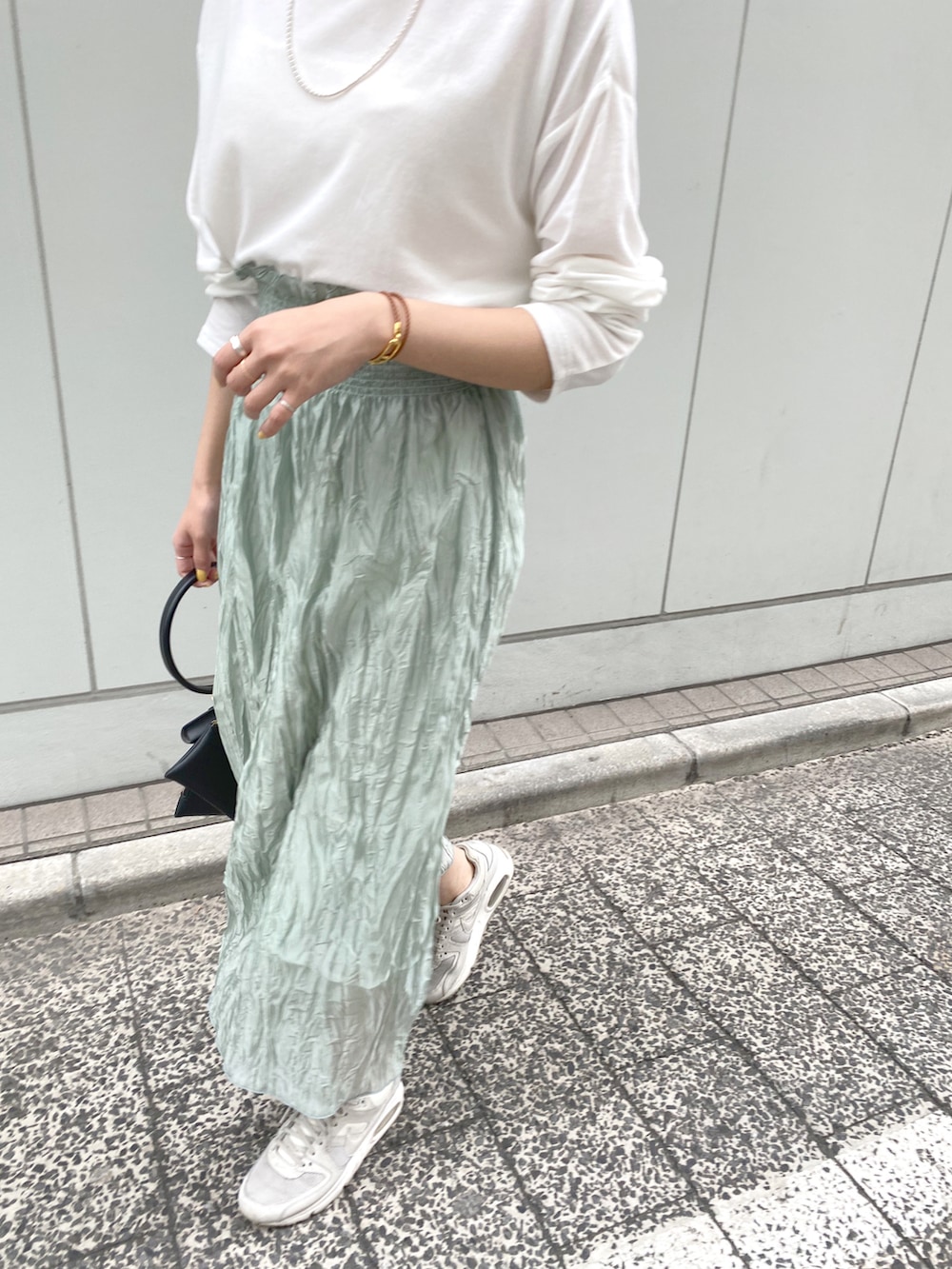 ホワイト系のTシャツ/カットソー、グリーン系のスカート、ブラック系のハンドバッグを着用したレディースの春コーディネートの4枚目の写真