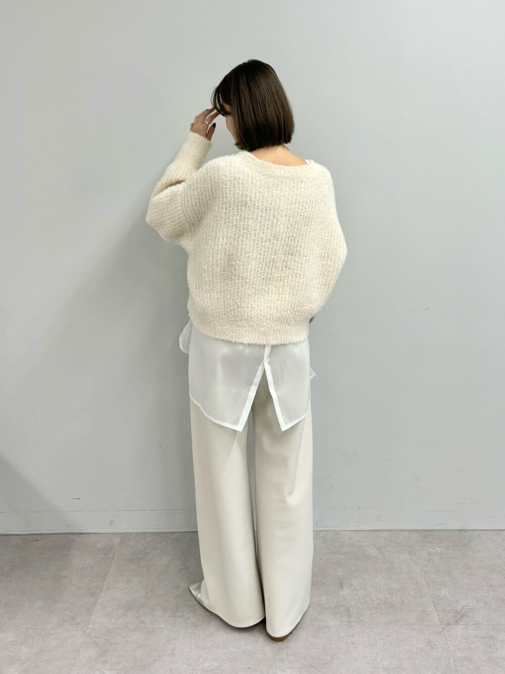 ブラウン系のトートバッグ、ホワイト系のニット/セーター、ホワイト系のシャツ/ブラウスを着用したレディースの冬コーディネートの2枚目の写真